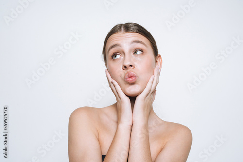 Beauty portrait of funny young girl with fresh skin tone showing kiss on white background isolated