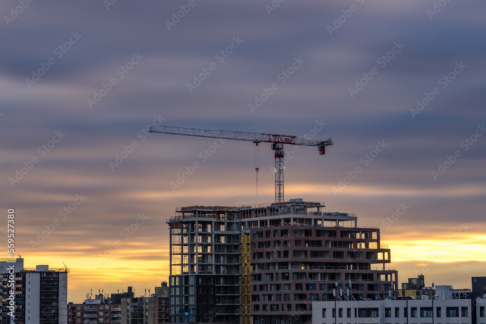 Colorful streaky sunset sky behind a large crane on top of construction site. Toronto Ontario