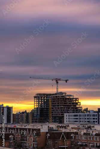 Colorful streaky sunset sky behind a large crane on top of construction site. Toronto Ontario