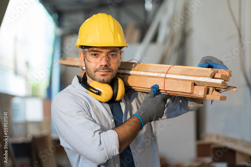 Fotografia Male carpenter carrying piece of wood on his shoulder at wood processing plants