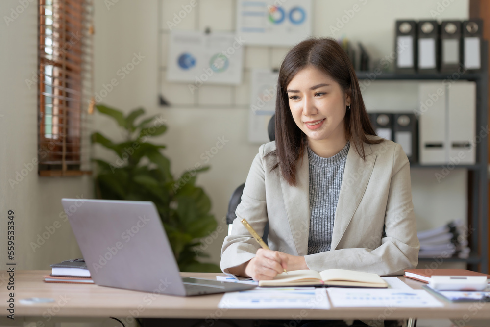 Beautiful Asian businesswoman using her laptop enjoying work, taking notes, reviewing work done. Beautiful Asian businesswoman using her laptop enjoying work, taking notes, reviewing work done.