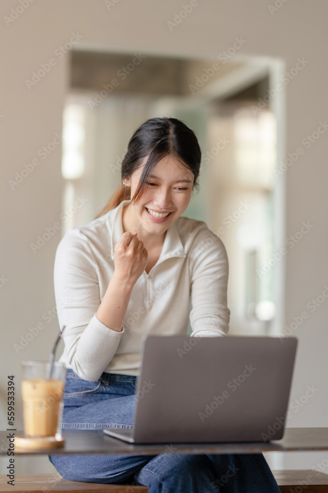 Young Asian woman working on a laptop glad the results were achieved satisfied and pleased with the accomplished work. Young Asian woman working on a laptop glad the results were achieved satisfied and pleased with the accomplished work.