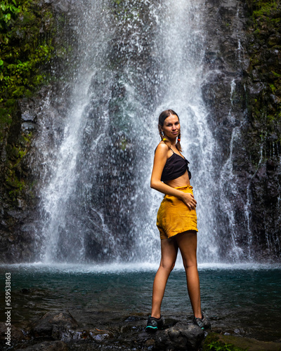 A beautiful girl stands under a tropical waterfall in Costa Rica  swimming in a hidden waterfall in the rainforest  don jose waterfalls