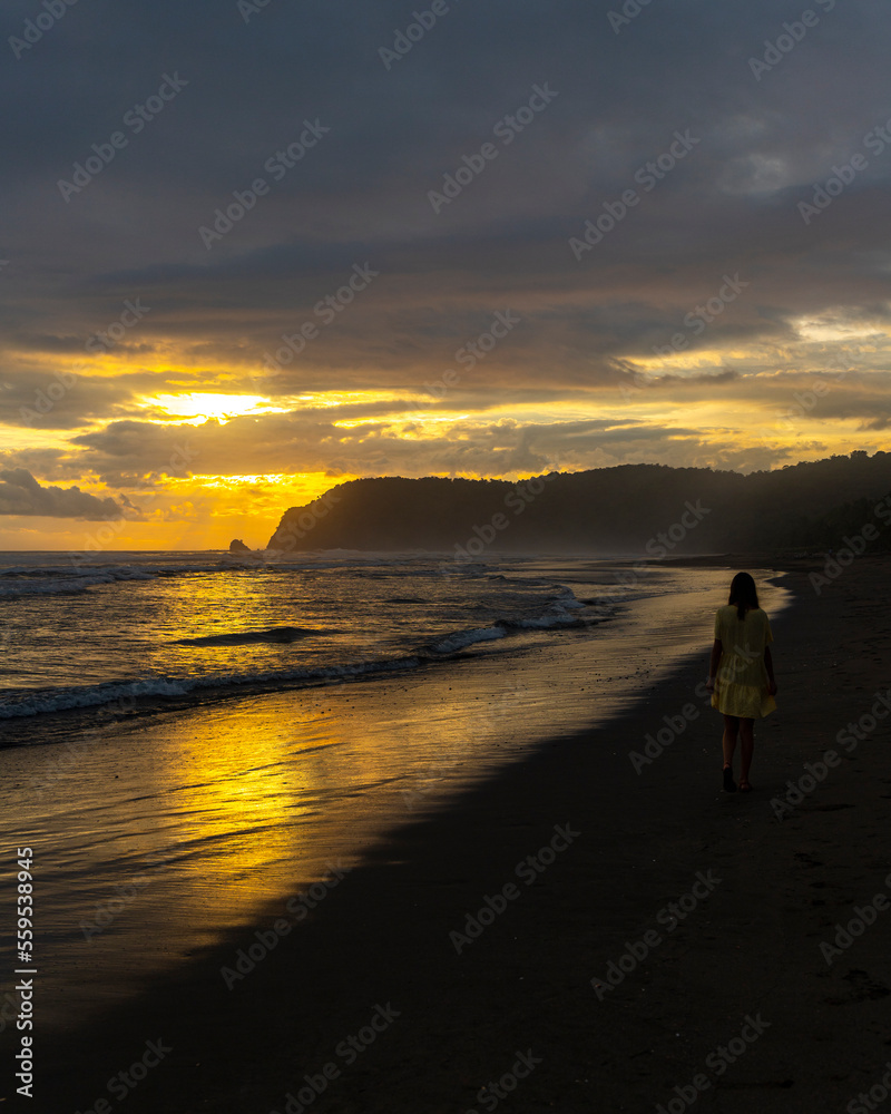 dark silhouette of a girl in a dress walking on a paradise Costa Rican beach at sunset; sunset on a tropical beach