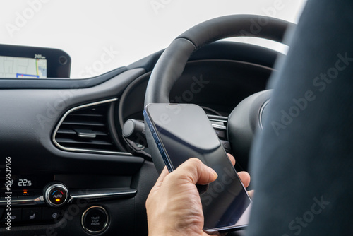 運転席でスマホを使う男性 © Haru Works