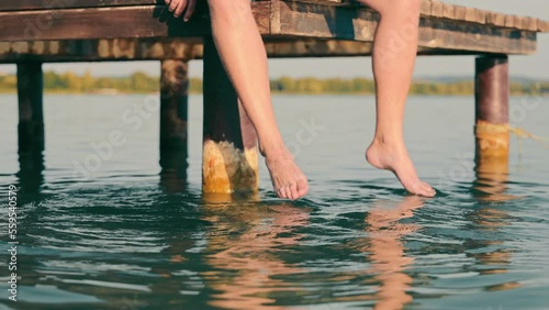 Wallpaper Mural Men's feet in the lake. A man sitting on a bridge with his legs dangling in the water. Torontodigital.ca