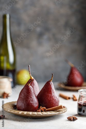 Pears in red wine on a plate with wine syrup and spices