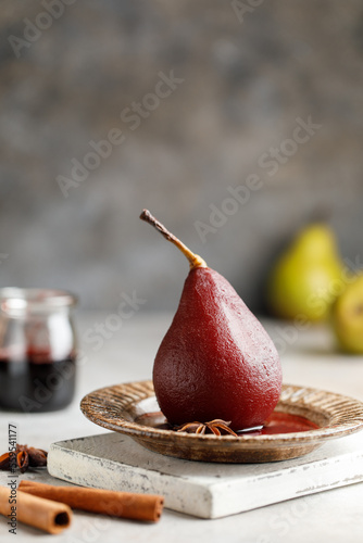 Pears in red wine on a plate with wine syrup and spices