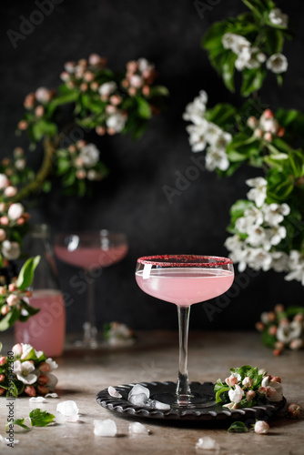 Spring and summer refreshing pink cocktail with apple blossom on light background. Pink summer cocktail