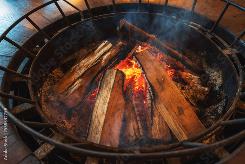 Burning firewood, fire and embers in stove for cooking or heating.