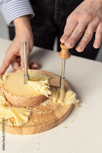 Round cheese knife. Tete de Moine. Woman cuts cheese. Girolle cheese knife. Cheese flowers closeup