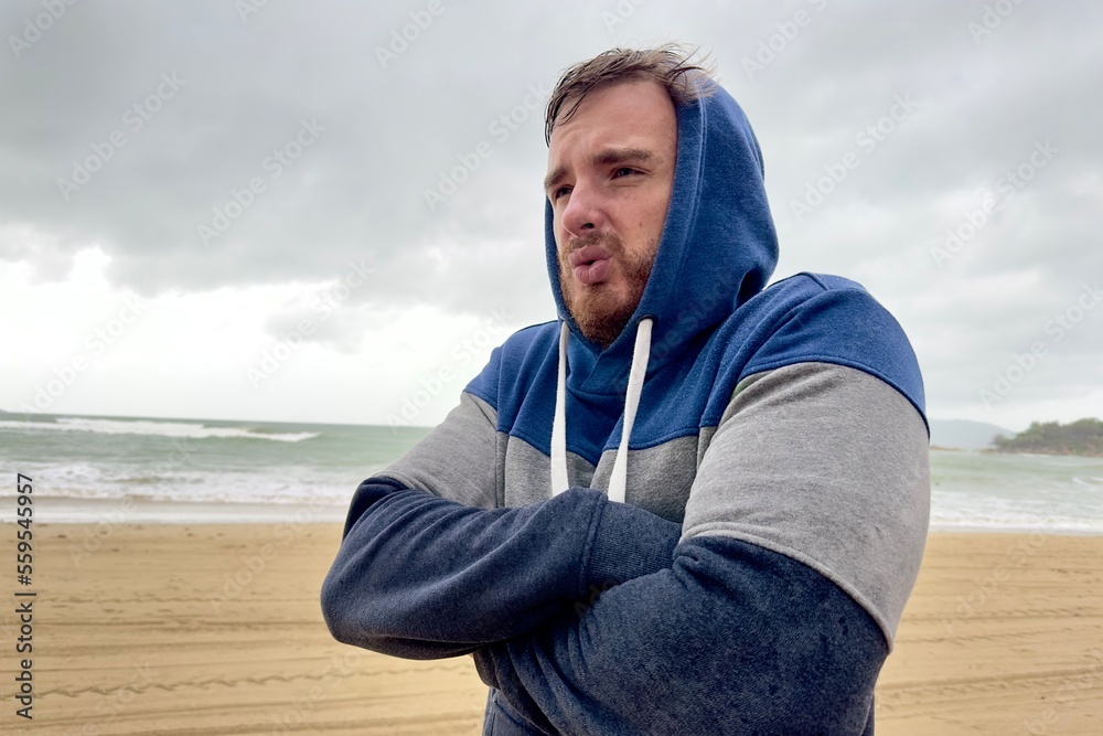 Portrait of unhappy depressed frozen trembling guy, young shivering from cold sad upset man on the sea beach, suffering from bad weather on summer vacation Portrait of unhappy depressed frozen trembling guy, young shivering from cold sad upset man on the sea beach, suffering from bad weather on summer vacation