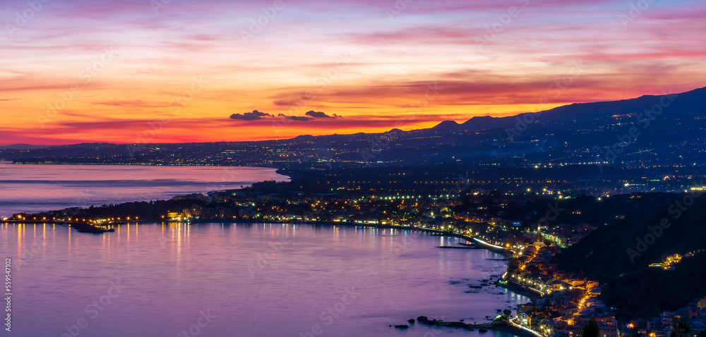 amazing night view from above to evening sea coast with many lights along the shore and picturesque sunset on background of night landscape