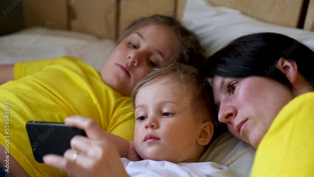 Happy family concept. Mom, daughter and son are play on bed. Child