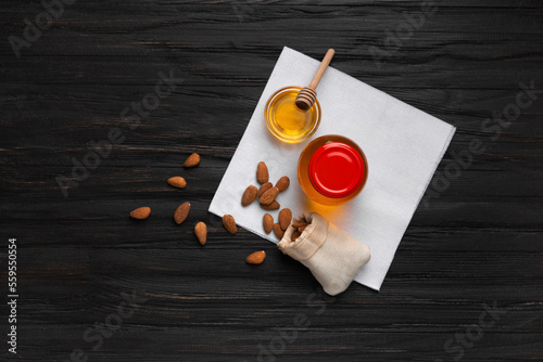 Honey in a bowl, dipper and almond nuts on a wooden background top view