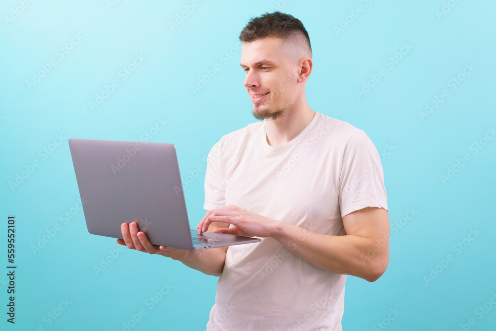 Smart young student smiling and using laptop on a blue background. Attractive. Casual. Cyberspace. Education. Entrepreneur. Internet. Leadership. Manager. Notebook. Pc. Professional. Web. Work Smart young student smiling and using laptop on a blue background. Attractive. Casual. Cyberspace. Education. Entrepreneur. Internet. Leadership. Manager. Notebook. Pc. Professional. Web. Work