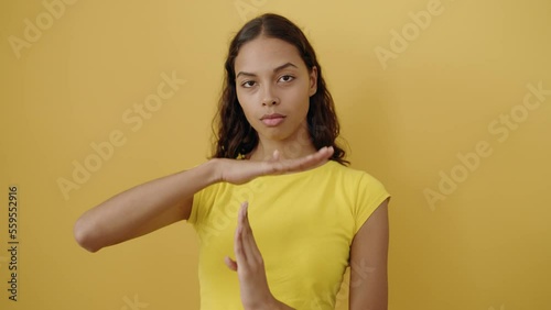 Young african american woman doing timeout gesture with hands over isolated yellow background photo