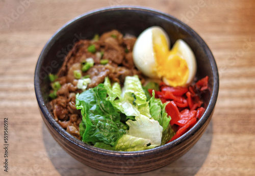 Beef Donburi Japanese rice, topped with yakiniku beef and egg serve in the table.