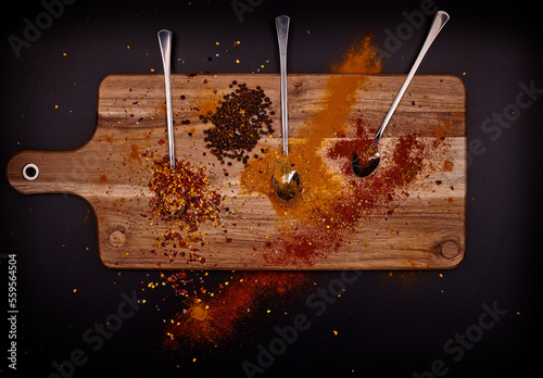 Condiment with spoons on wood and black background.