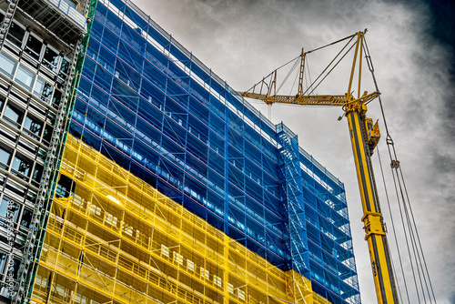 Baustelle mit Gerüst und Bauschutznetz in den Nationalfarben der Ukraine als Symbol für den Wiederaufbau an einem Gebäude in der Frankfurter Innenstadt
