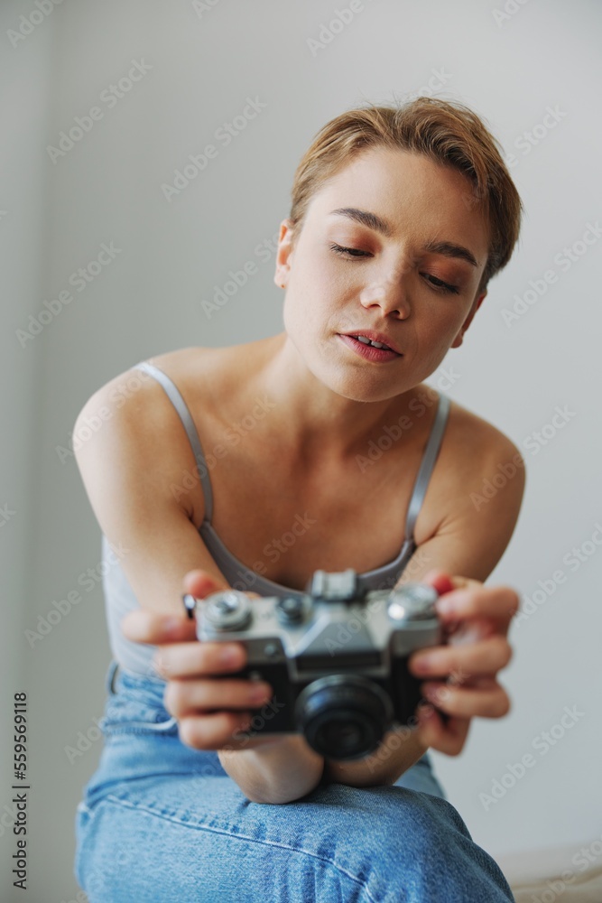 Woman photographer shooting in studio on old film camera at home on couch portrait, white background, free copy space, freelance photographer Woman photographer shooting in studio on old film camera at home on couch portrait, white background, free copy space, freelance photographer