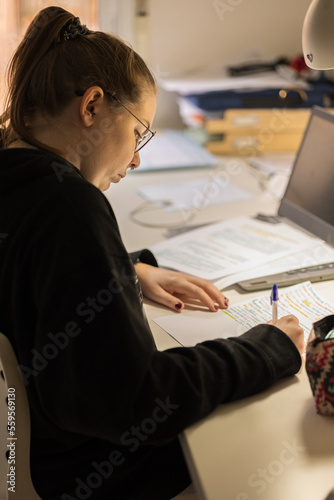 Blur effect. Young blonde girl, studying at home with a computer and typing. 