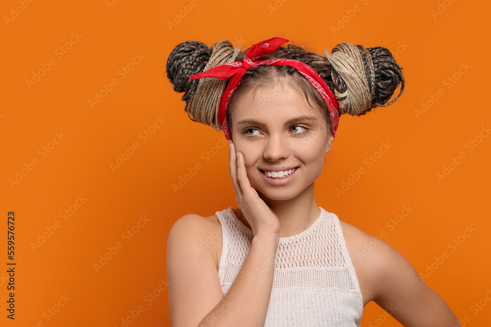 Beautiful woman with braided double buns on orange background, space for text Beautiful woman with braided double buns on orange background, space for text