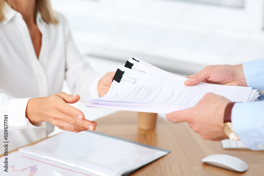 Man giving documents to colleague in office, closeup Man giving documents to colleague in office, closeup