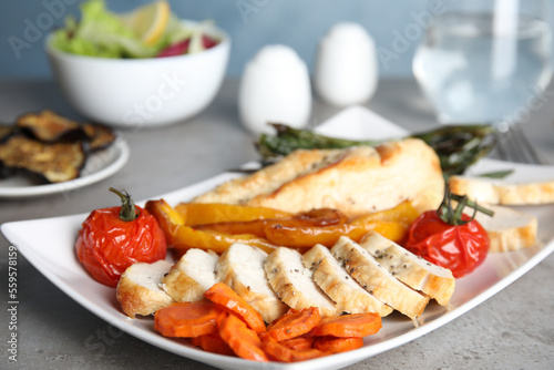 Tasty cooked chicken fillet and vegetables served on grey table. Healthy meals from air fryer