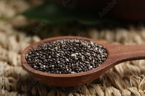 Wooden spoon with chia seeds on wicker stand, closeup