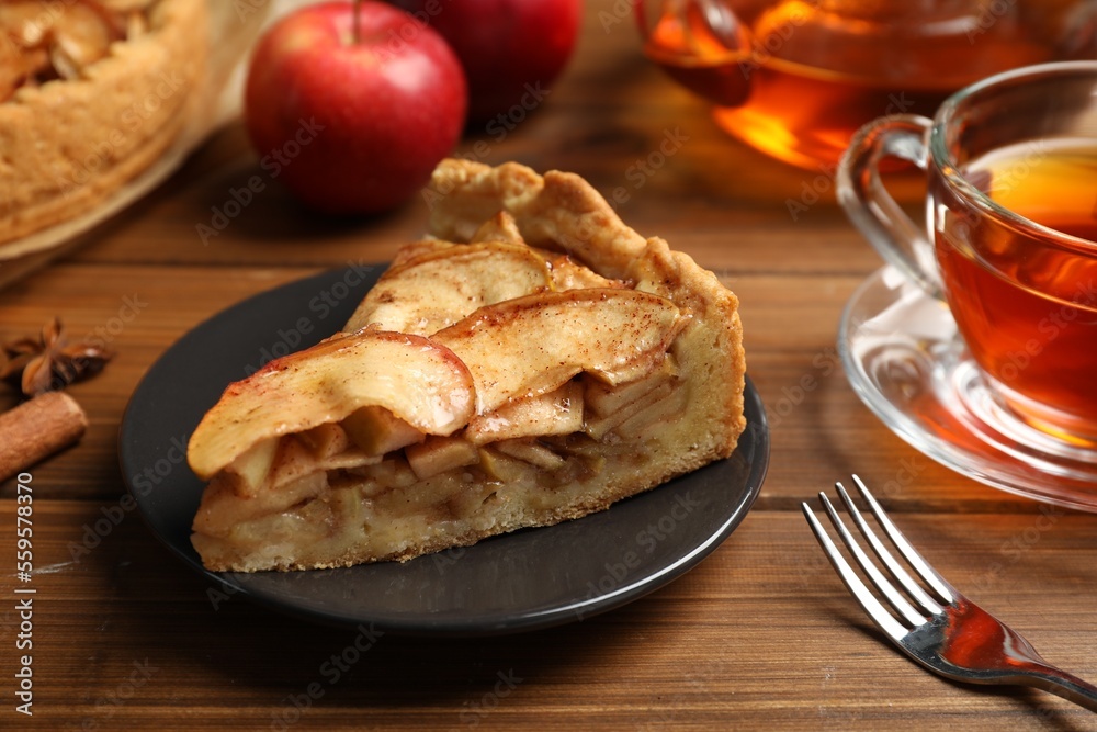 Slice of delicious apple pie served with tea on wooden table, closeup Slice of delicious apple pie served with tea on wooden table, closeup