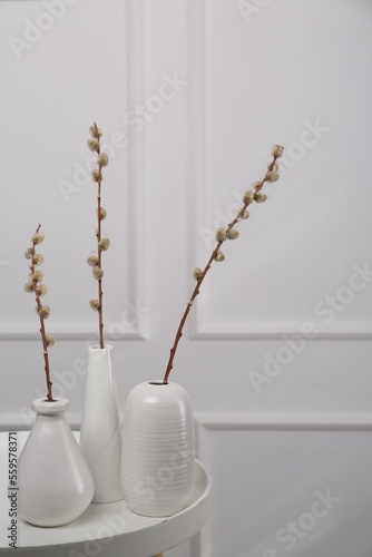Beautiful pussy willow branches in vases on white table indoors