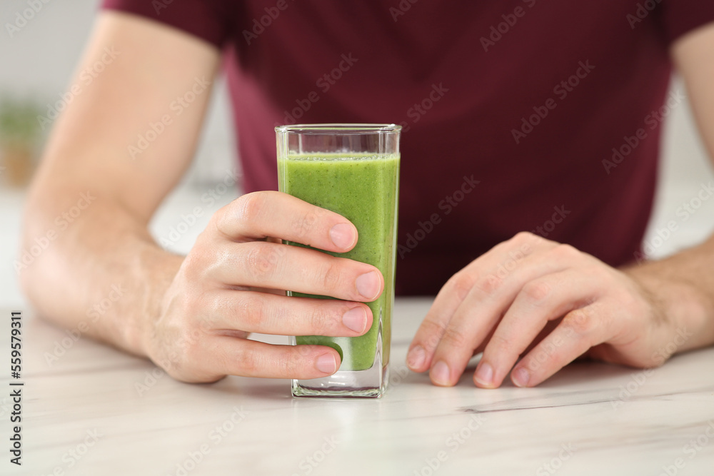 Man drinking delicious fresh smoothie at white marble table indoors, closeup Man drinking delicious fresh smoothie at white marble table indoors, closeup