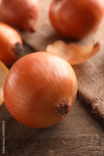 Many ripe onions on wooden table, closeup