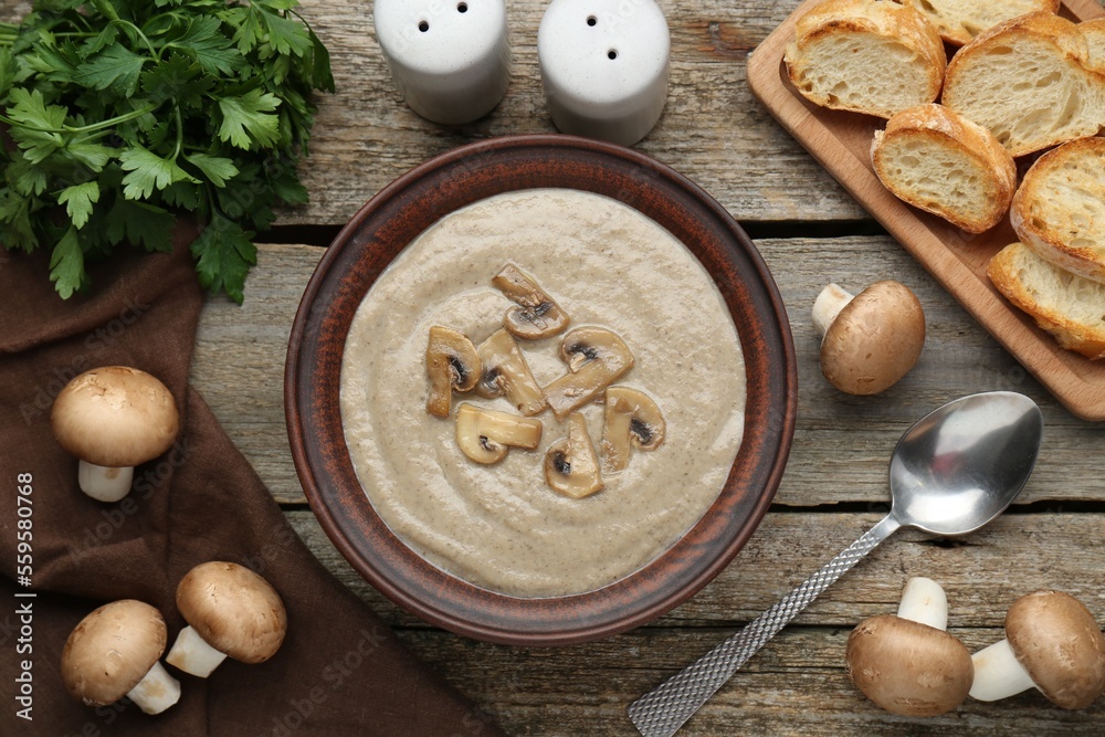 Fototapeta premium Delicious mushroom cream soup served on wooden table, flat lay