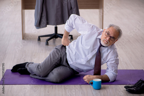 Old male employee doing sport exercises during break