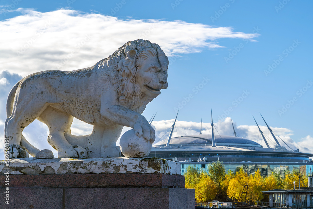 Sculpture of a lion with a ball on the background of the Zenit Arena building. Elagin Island. Saint-Petersburg.