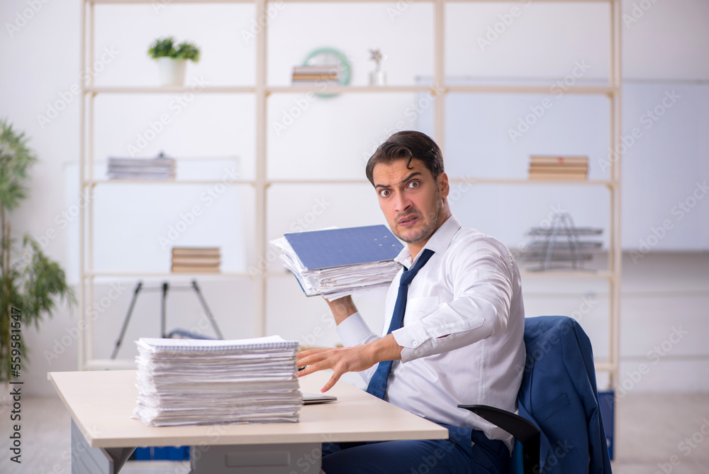 Young male employee and too much work in the office Young male employee and too much work in the office