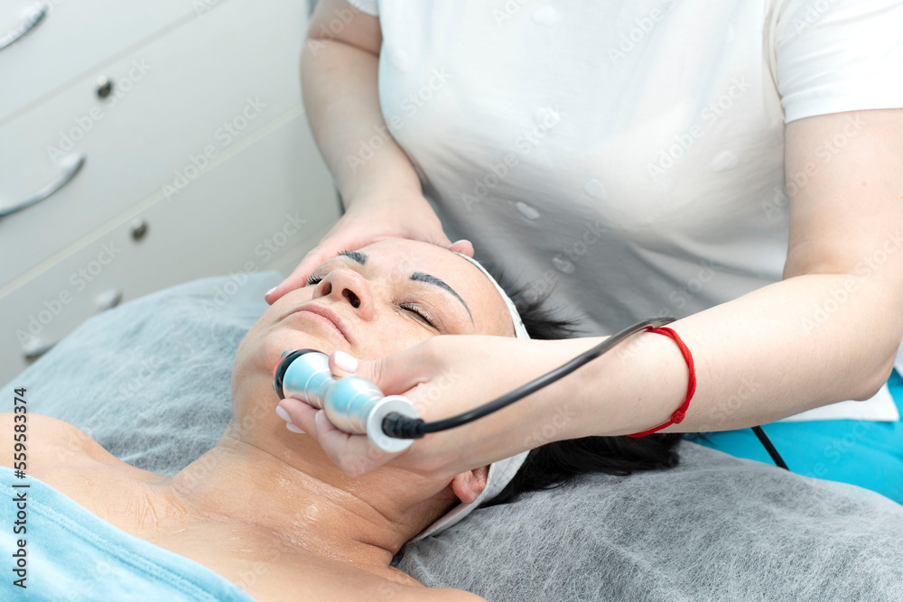 Naklejka premium Health. Cosmetology. An aged woman lies on a couch in a beauty salon for a facelift procedure.
