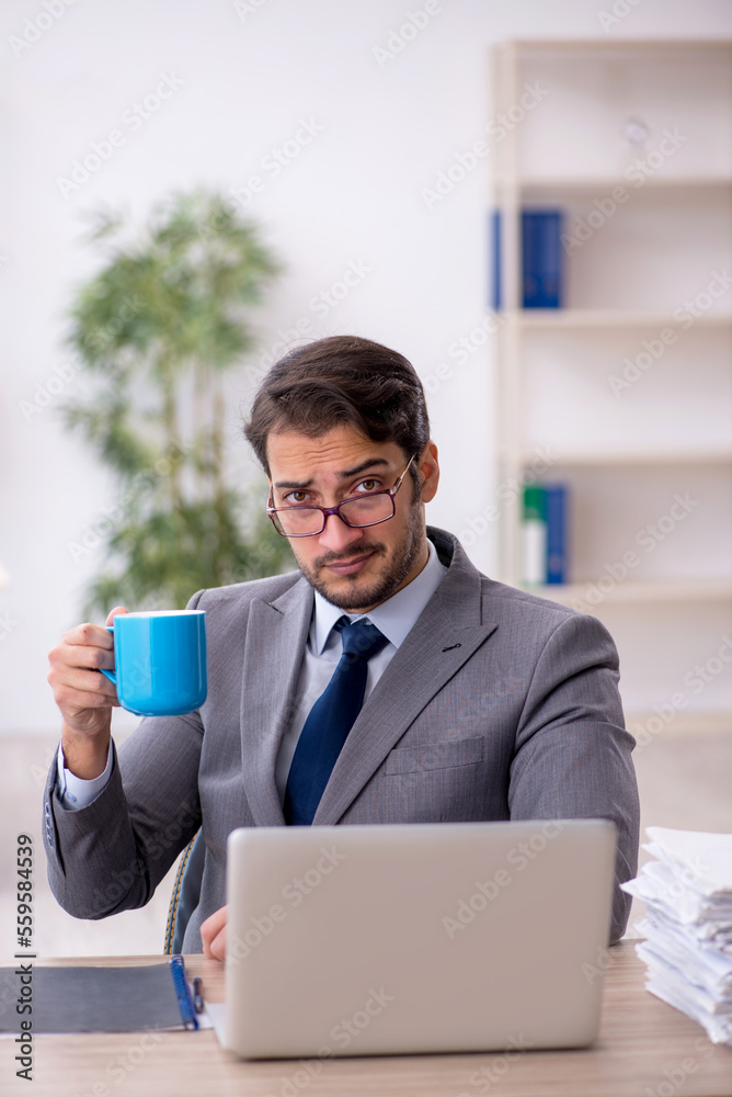 Young male employee drinking coffee during break Young male employee drinking coffee during break