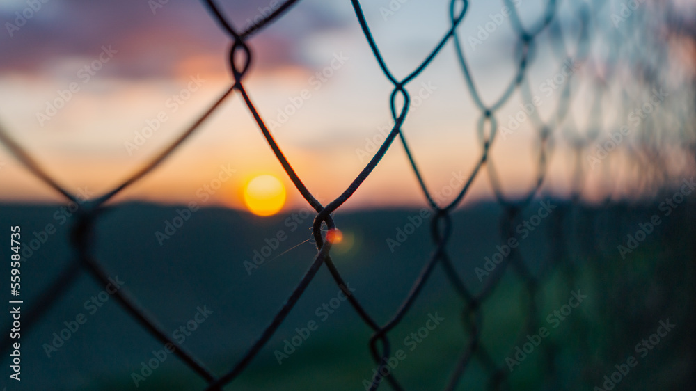 Beautiful colorful sunset through the fence Beautiful colorful sunset through the fence