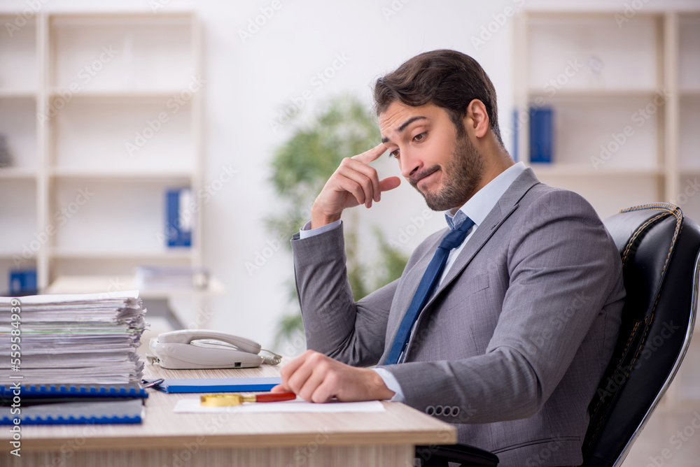 Young male employee and too much work in the office Young male employee and too much work in the office