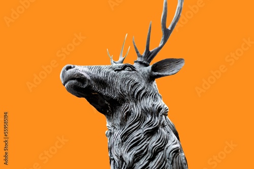 Head of a noble and beautiful and traditional british Deer Stag bronze  or alloy statue or sculpture cut out against a orange background