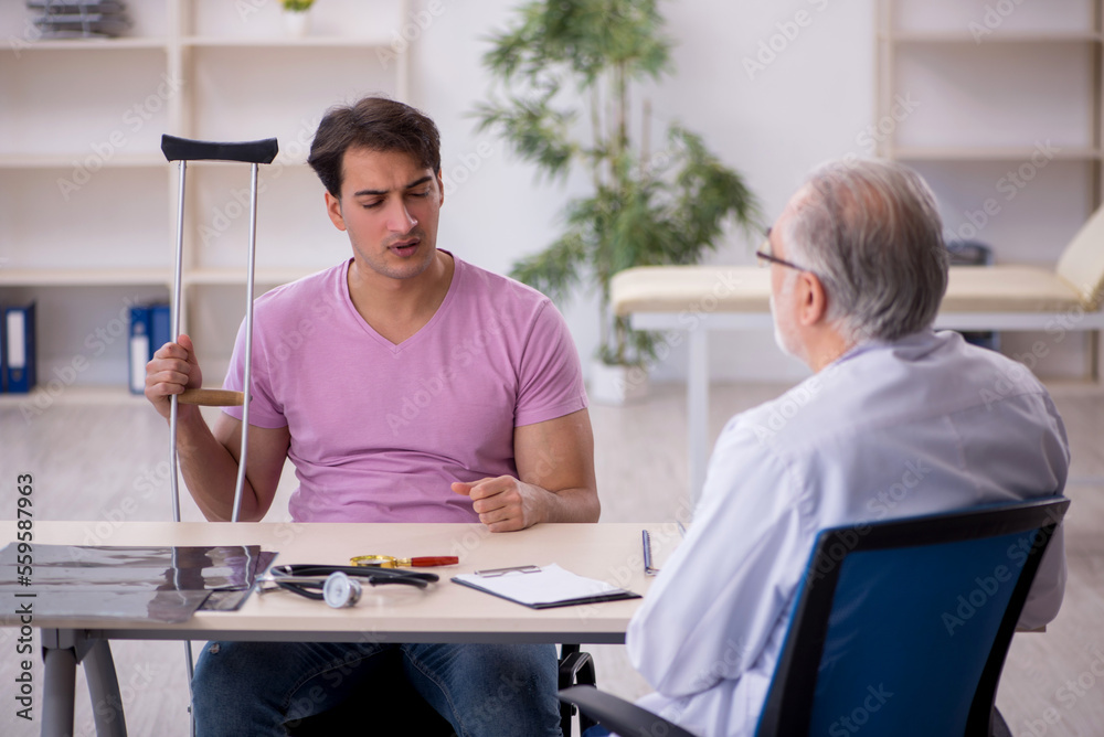 Young leg injured patient visiting old male doctor Young leg injured patient visiting old male doctor