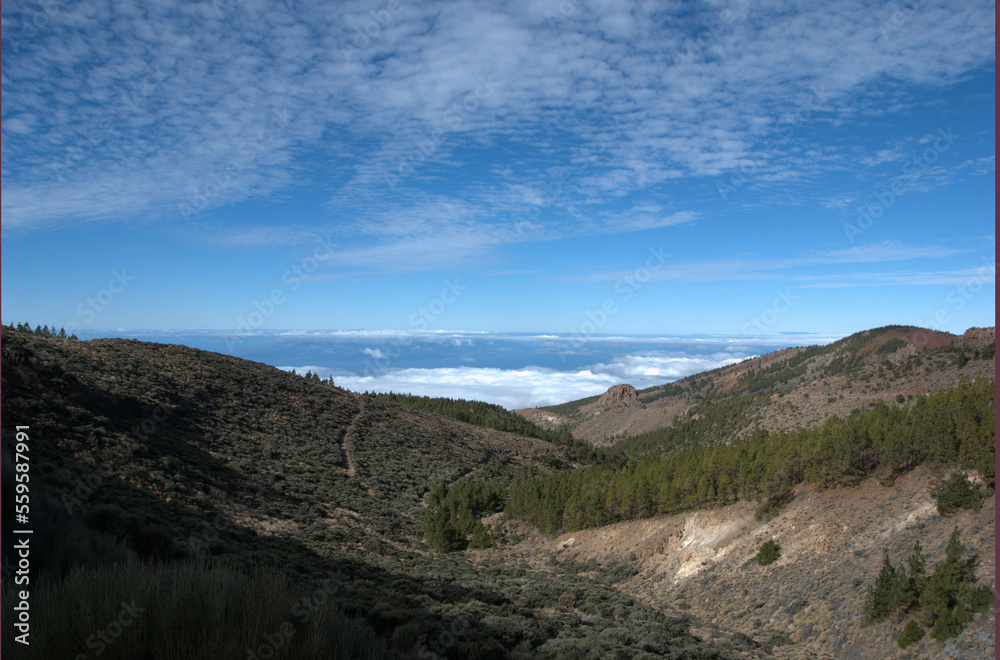 Landscape to the horizon with white clouds above and bellow. View from mountains. Scenic view with ocean, clouds and rocks.