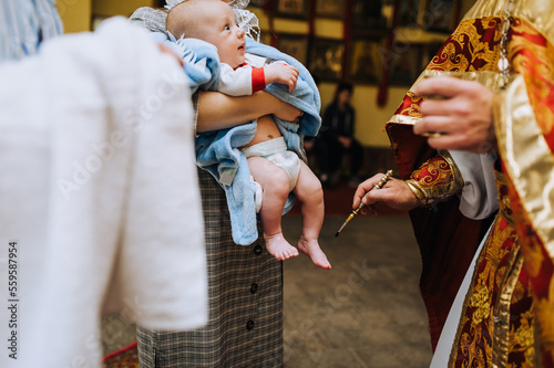 Foto A priest, a Christian in a church conducts a rite, a baptismal ritual with an infant, a child - anointing with oil