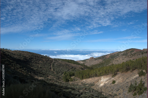 Landscape to the horizon with white clouds above and bellow. View from mountains. Scenic view with ocean, clouds and rocks.