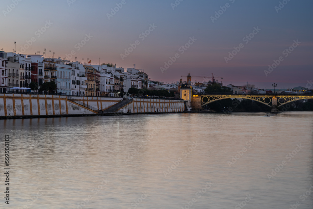 Obraz premium Sunset over the authentic neighborhood of Tirana in Seville with views on Calle Betis, Torre Sevilla and with awesome reflections in the river Guadalquivir, creating magic atmosphere and views