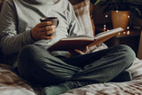 A caucasian man relaxing at home, reading a book, drinking coffee in bed