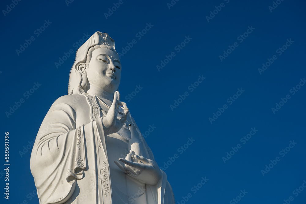 Detail of Lady Buddha statue in a Buddhist temple and blue sky background in Danang, Vietnam.